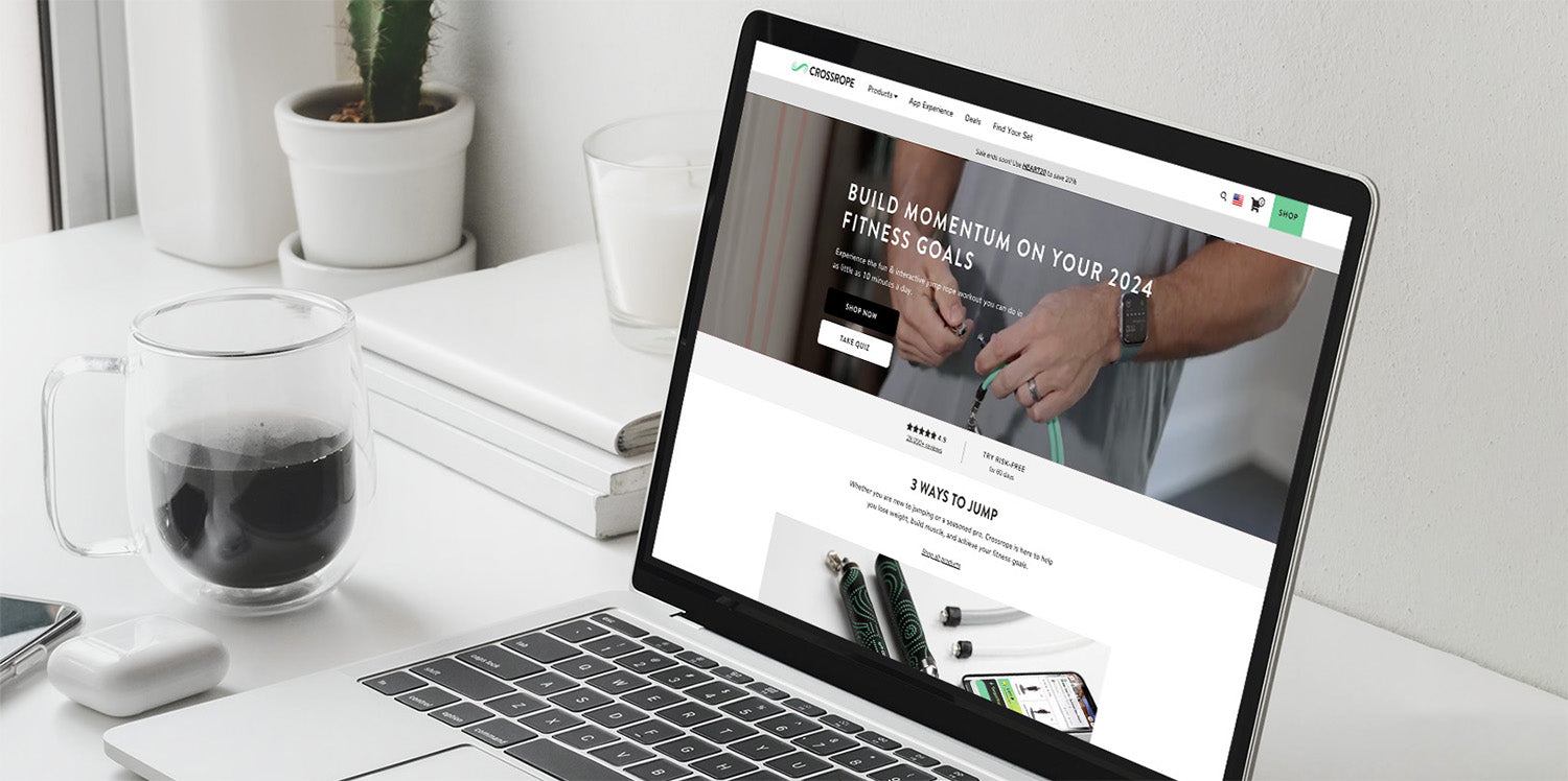 Laptop on desk showing CROSSROPE site: BUILD MOMENTUM ON YOUR 2024 FITNESS GOALS; SHOP NOW; TAKE QUIZ; 3 WAYS TO JUMP.