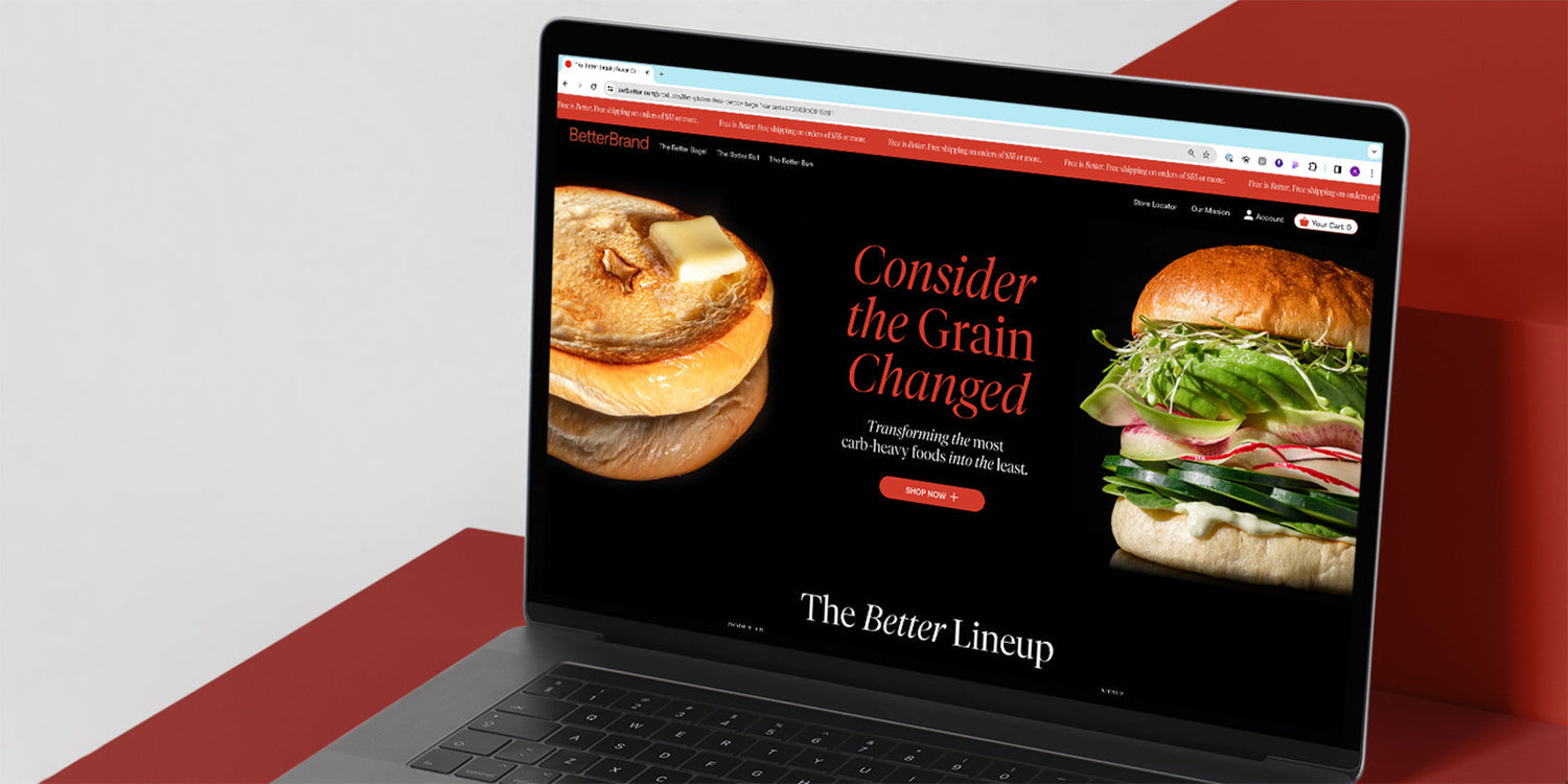 Laptop showing BetterBrand with headline 'Consider the Grain Changed' 'SHOP NOW +' and 'The Better Lineup'