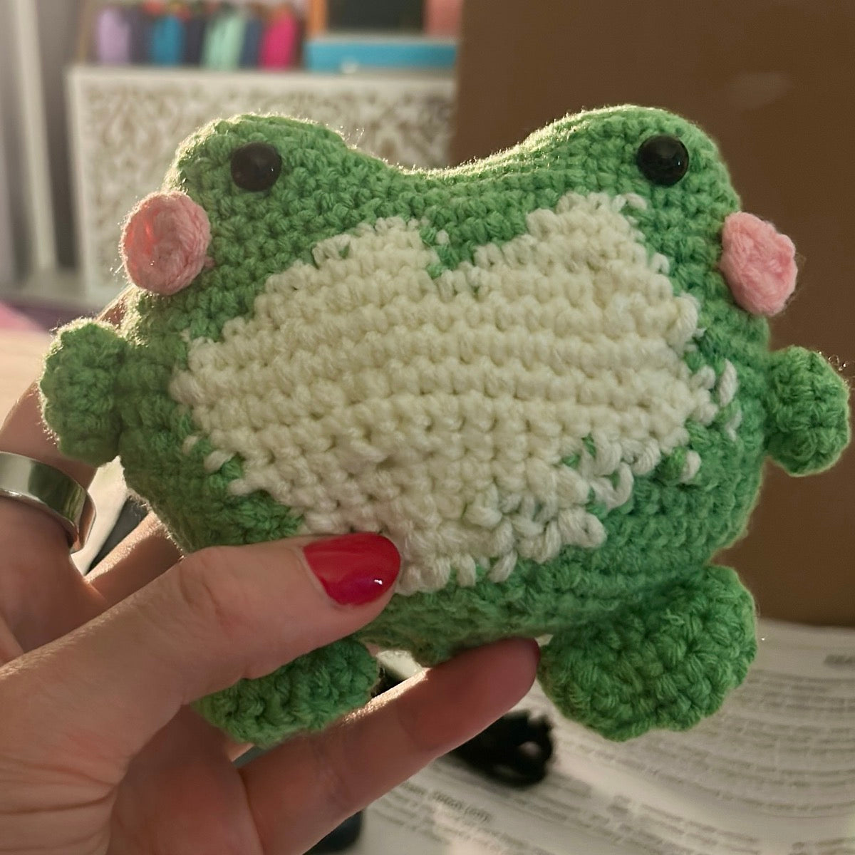 Trevor, a green crocheted frog plushie held in a hand